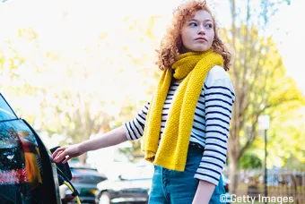 Une femme avec un foulard jaune recharge une voiture électrique